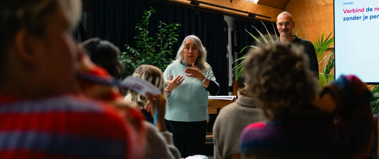 Trainer geeft live groepsworkshop om stress te verlagen en verzuim te voorkomen